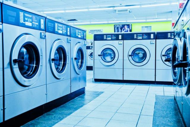 Trier le linge avant lavage Pile de linge trié par couleur devant un lave-linge ouvert